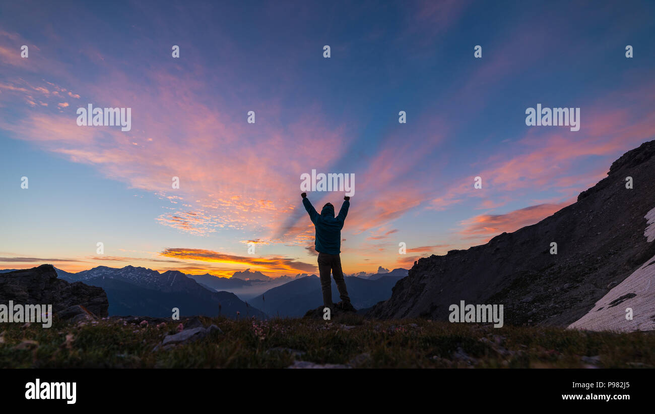 Mann, der auf dem Berg oben Anheben der Arme, sunrise licht bunt Sky scenis Landschaft, die Eroberung des Erfolg LEADER-Konzept. Stockfoto