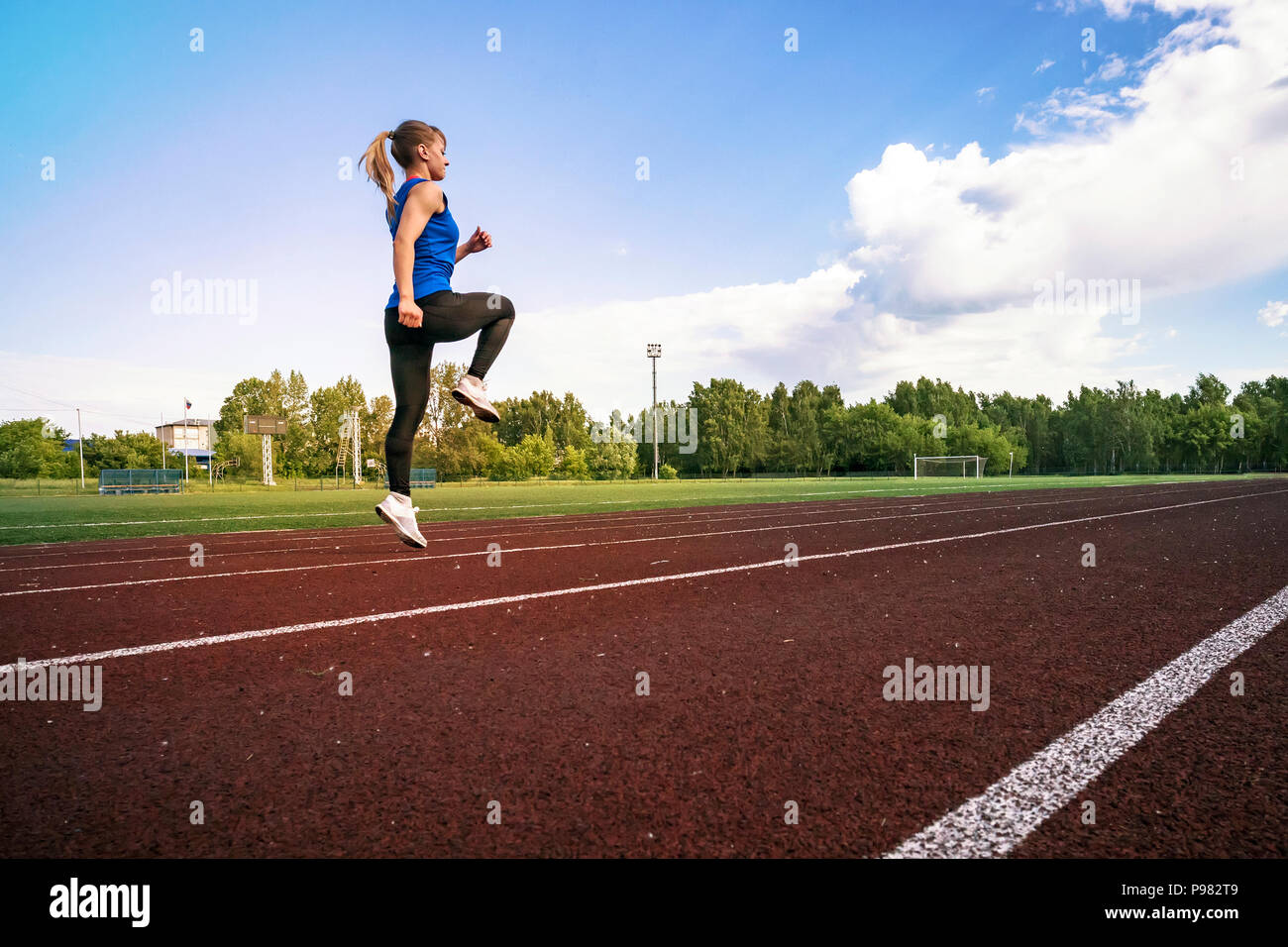 Seitenansicht eines passen junge blonde Frau, Jogging im Stadion. Ein junger Athlet läuft in Sportswear im Stadion in den frühen Morgen. Stockfoto