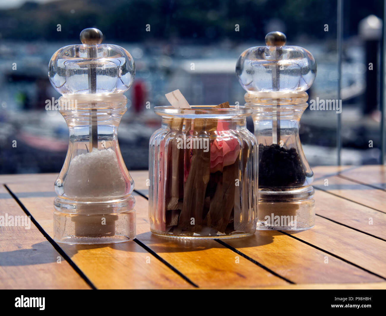 Salz und Pfeffer Mühlen zusammen mit einem Glas mit Zucker stand auf dem Tisch in einem Hafen Cafe. Stockfoto