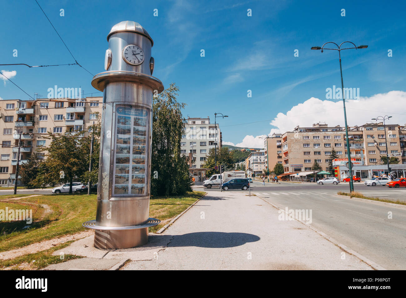 Ein kleiner zylindrischer Gedenkuhrturm mit Archivfotos an einer Straßenbahnhaltestelle im äußersten Sarajevo, Bosnien und Herzegowina Stockfoto