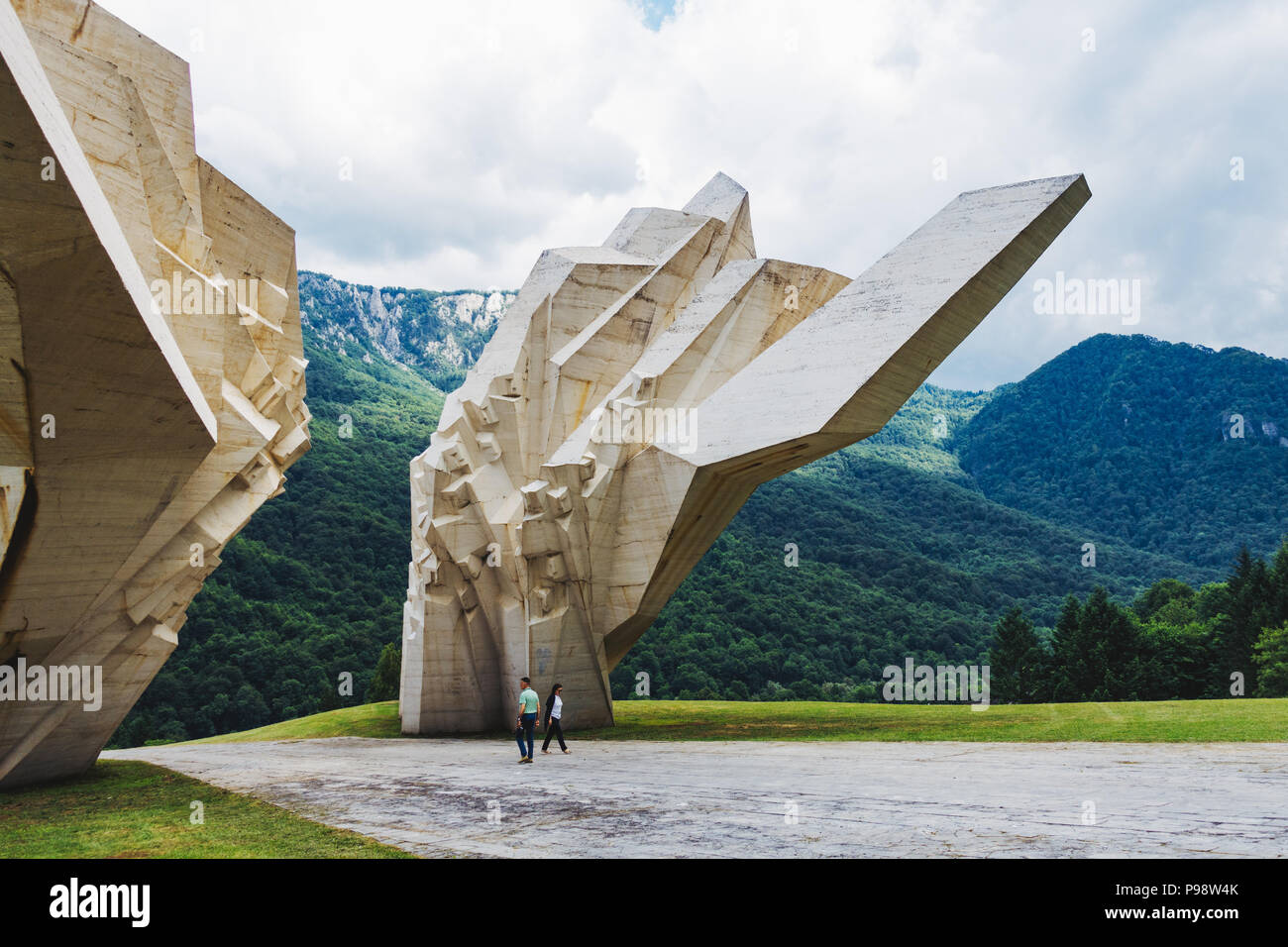 Zwei Touristen sind von dem großen weißen Tjentište spomenik im Nationalpark Sutjeska, Bosnien und Herzegowina in den Schatten gestellt (jugoslawischen Krieg Denkmal) Stockfoto