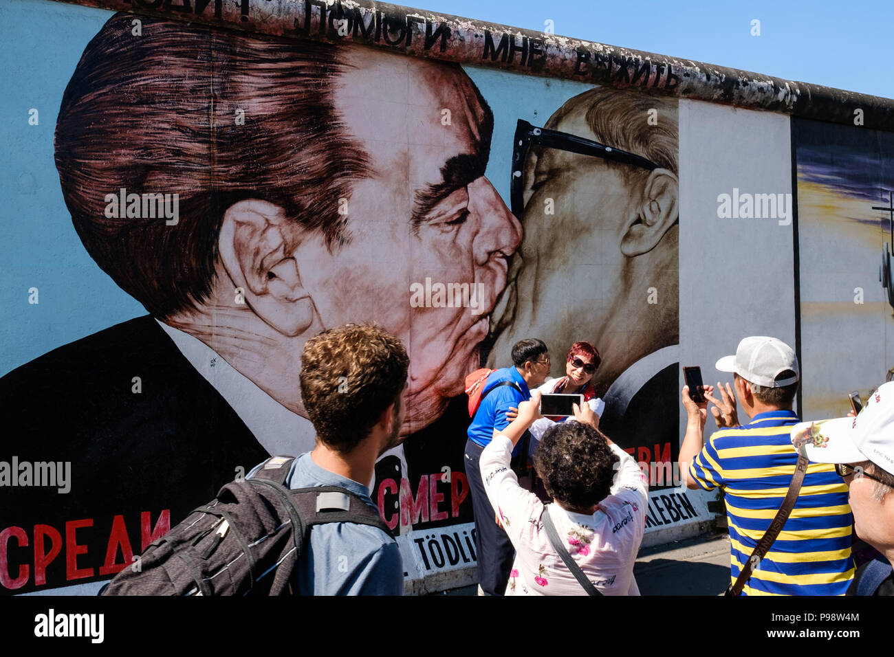 Berlin, Deutschland - Juli 2018: Touristen an der Berliner Mauer/East Side Gallery vor Dimitri Vrubel' Malerei posing - der die brüderliche Kuss (Germa Stockfoto