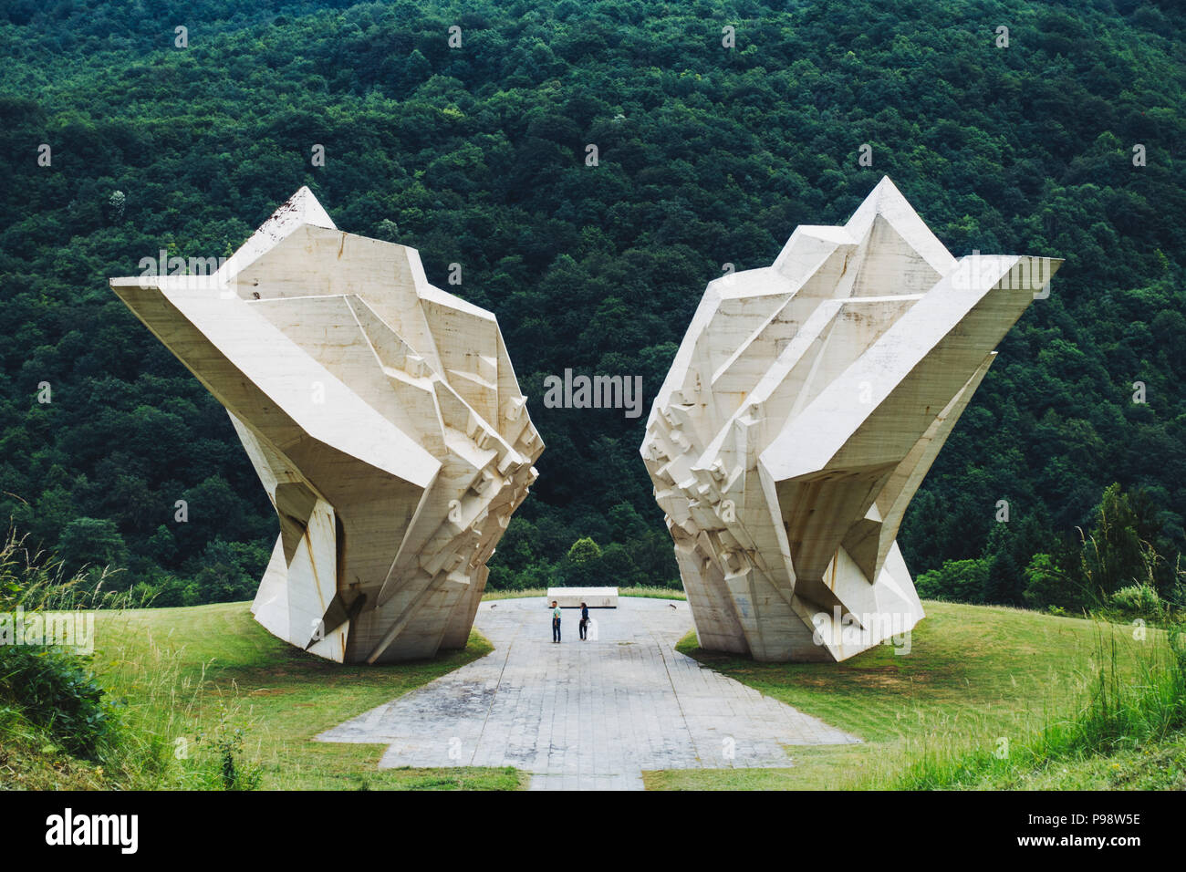 Zwei Touristen sind von dem großen weißen Tjentište spomenik im Nationalpark Sutjeska, Bosnien und Herzegowina in den Schatten gestellt (jugoslawischen Krieg Denkmal) Stockfoto