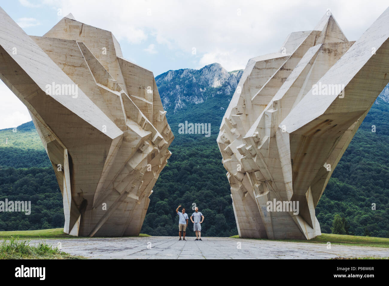 Zwei Touristen sind von dem großen weißen Tjentište spomenik im Nationalpark Sutjeska, Bosnien und Herzegowina in den Schatten gestellt (jugoslawischen Krieg Denkmal) Stockfoto