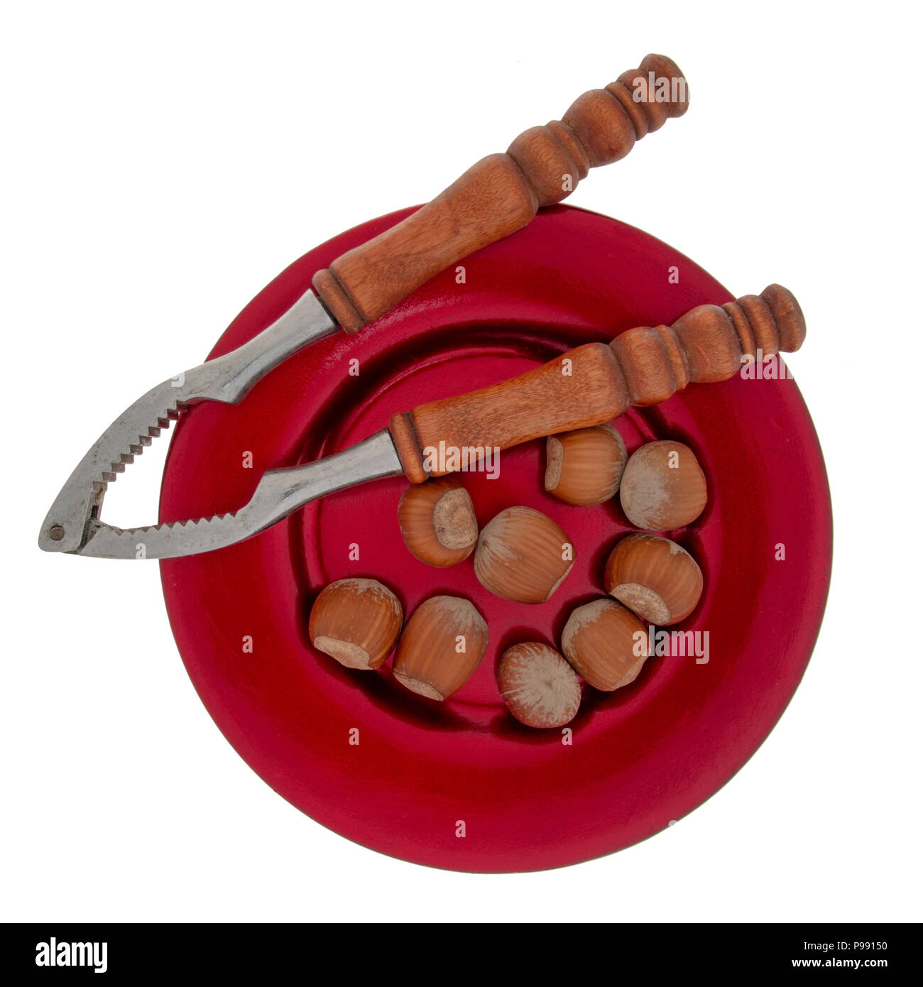 Nussknacker und ganzen Haselnüssen auf festlichen roten Platte, auf weißem Hintergrund. Typische Weihnachten, saisonale behandeln. Stockfoto