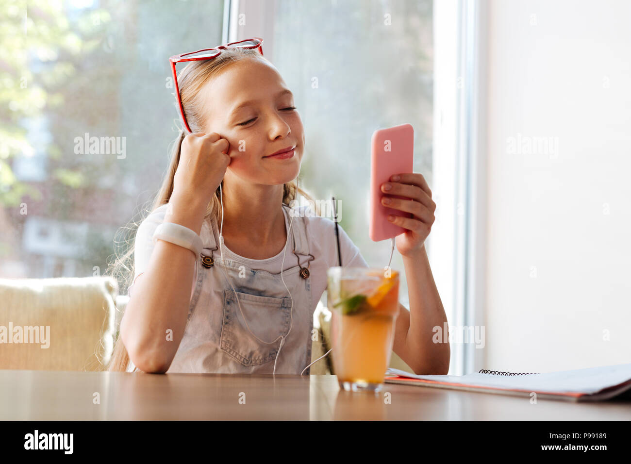 Moderne schoolgirl Videos anschauen, während im Cafe sitzen Stockfoto
