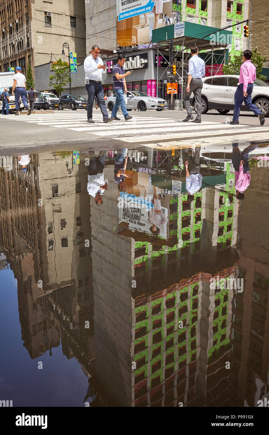 New York City, USA - Juni 28, 2018: die Menschen zu Fuß durch die Fußgängerzone überqueren in einer Pfütze in Midtown Manhattan nieder. Stockfoto