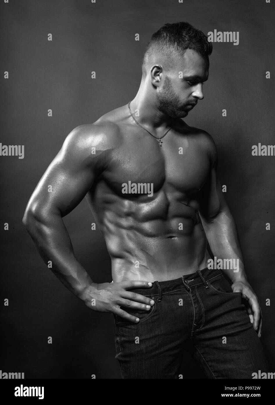 Stattlich sexy Bodybuilder/male Fitnessmodel wirft mit Tropfen des Wassers auf seinem Körper Stockfoto