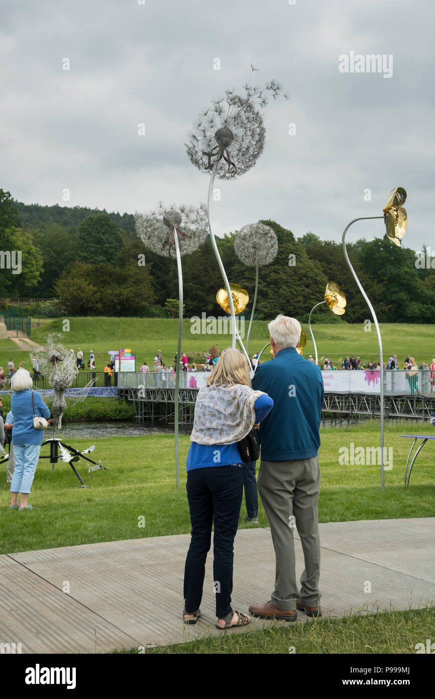 Leute, die bei Anzeige der ursprünglichen Metall & wire flower Skulpturen als Besucher Brücke - RHS Chatsworth Flower Show, Derbyshire, England, UK. Stockfoto