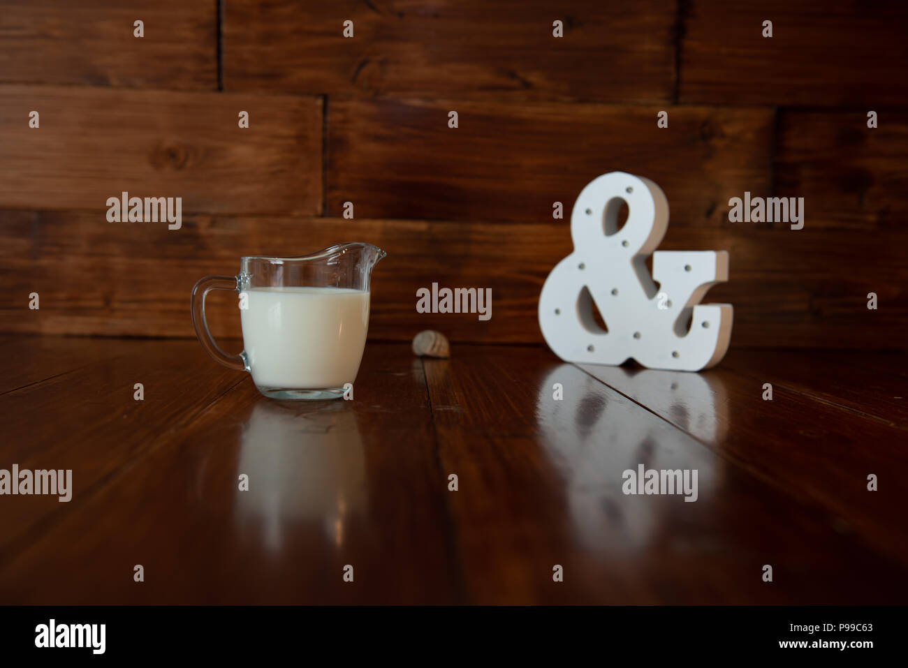 Milch in Glas Milchkännchen und eine glühende kaufmännisches Und-Zeichen Stockfoto