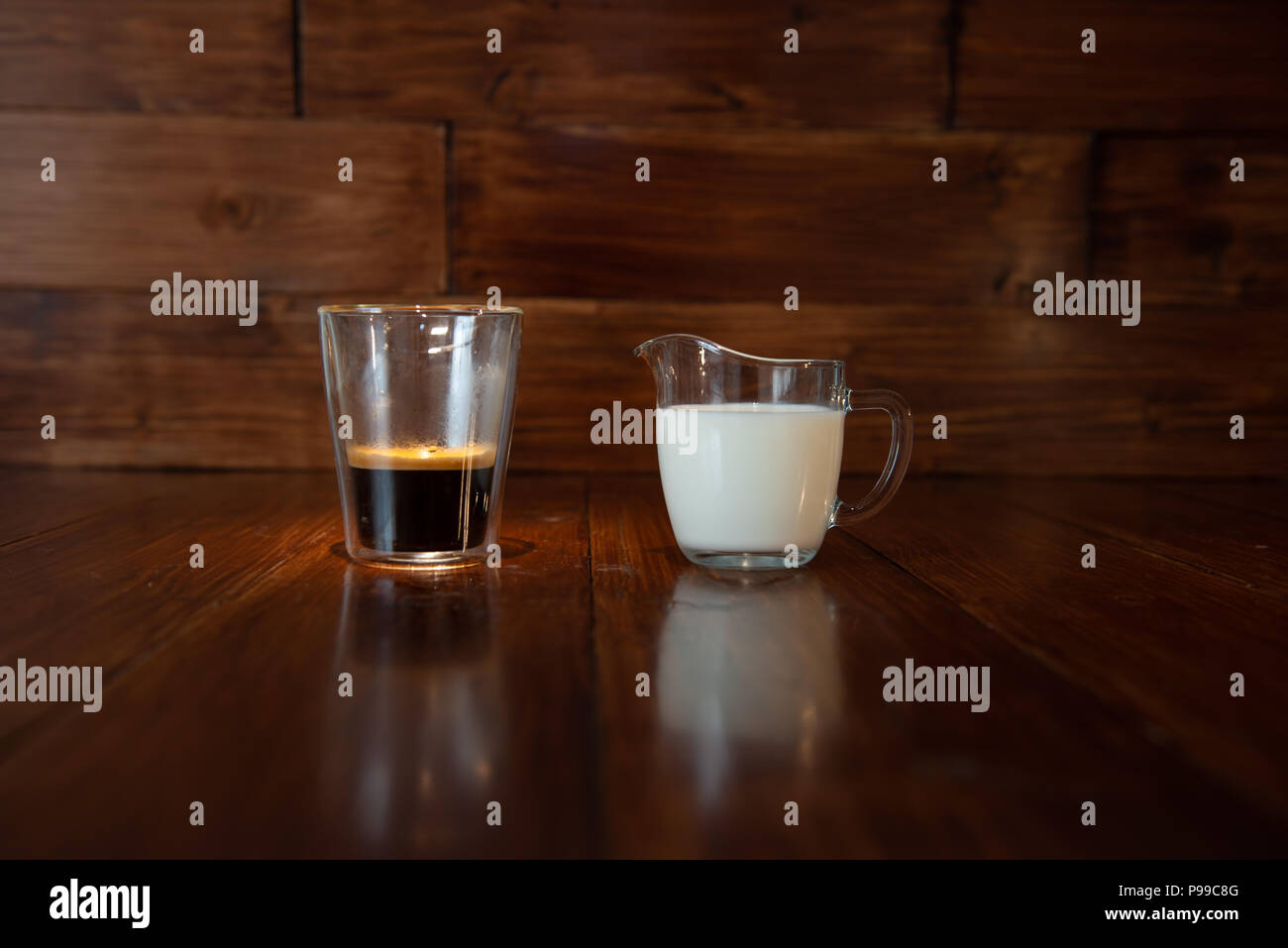 Milch in Glas Milchkännchen mit einer Tasse Kaffee in einem durchsichtigen Glas Stockfoto