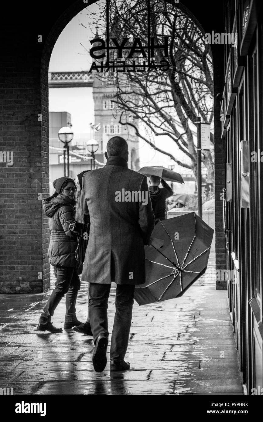 London Mann mit Regenschirm mit Tower Bridge im Hintergrund Stockfoto