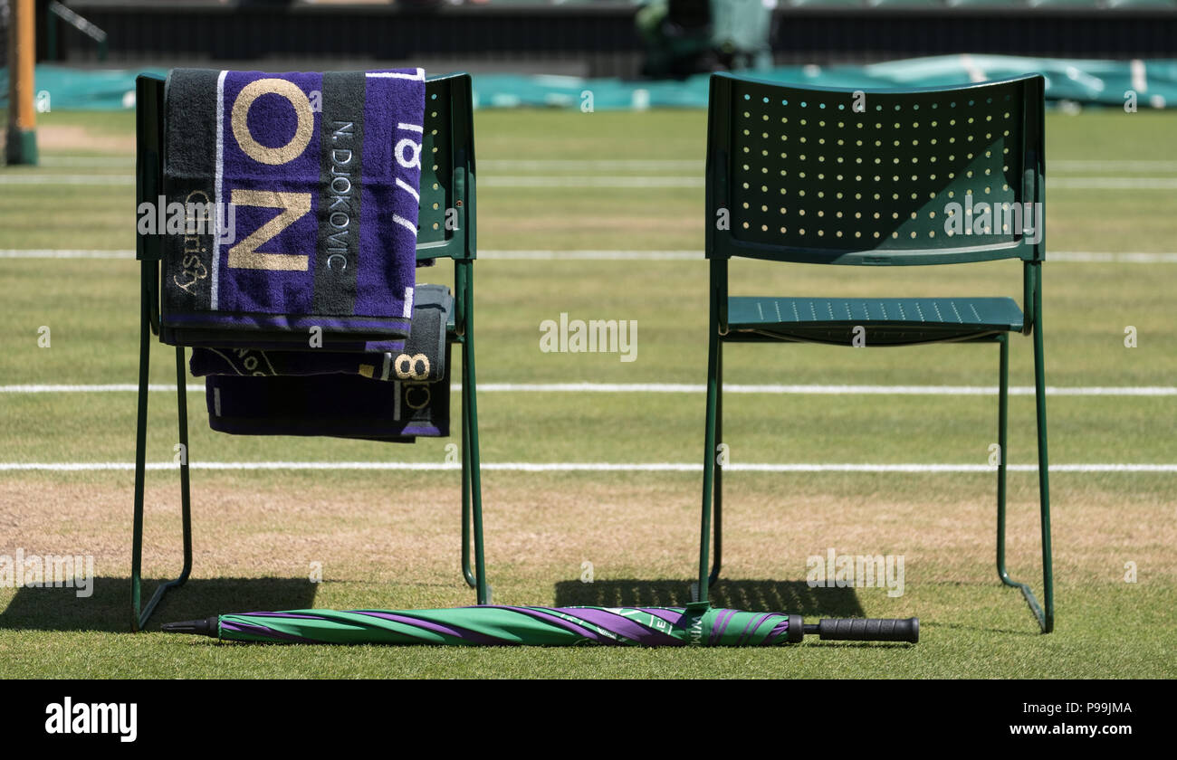 Stühle Spieler mit Handtuch über den Rücken gefaltet, und eine grüne und lila Schirm auf dem Boden. Handtuch hat den Namen von Djokovic. Stockfoto