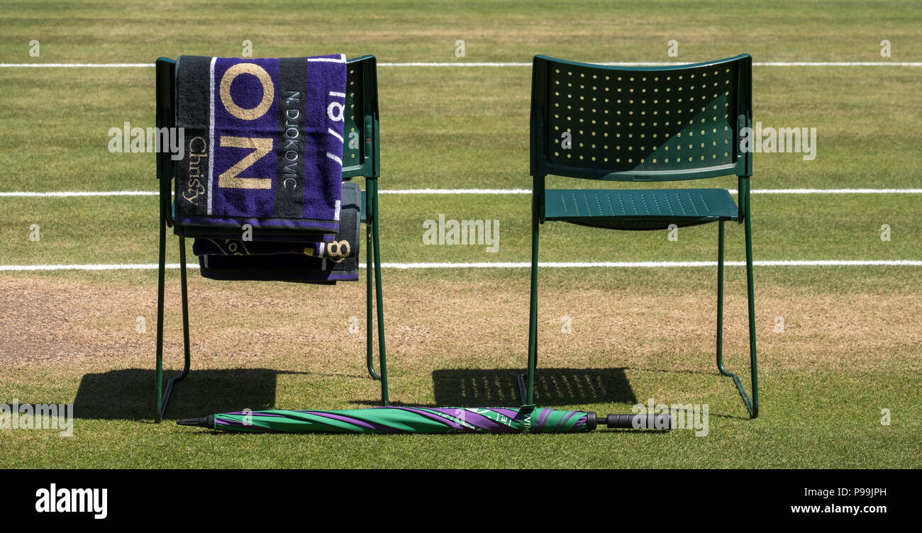 Stühle Spieler mit Handtuch über den Rücken gefaltet, und eine grüne und lila Schirm auf dem Boden. Handtuch hat den Namen von Djokovic. Stockfoto