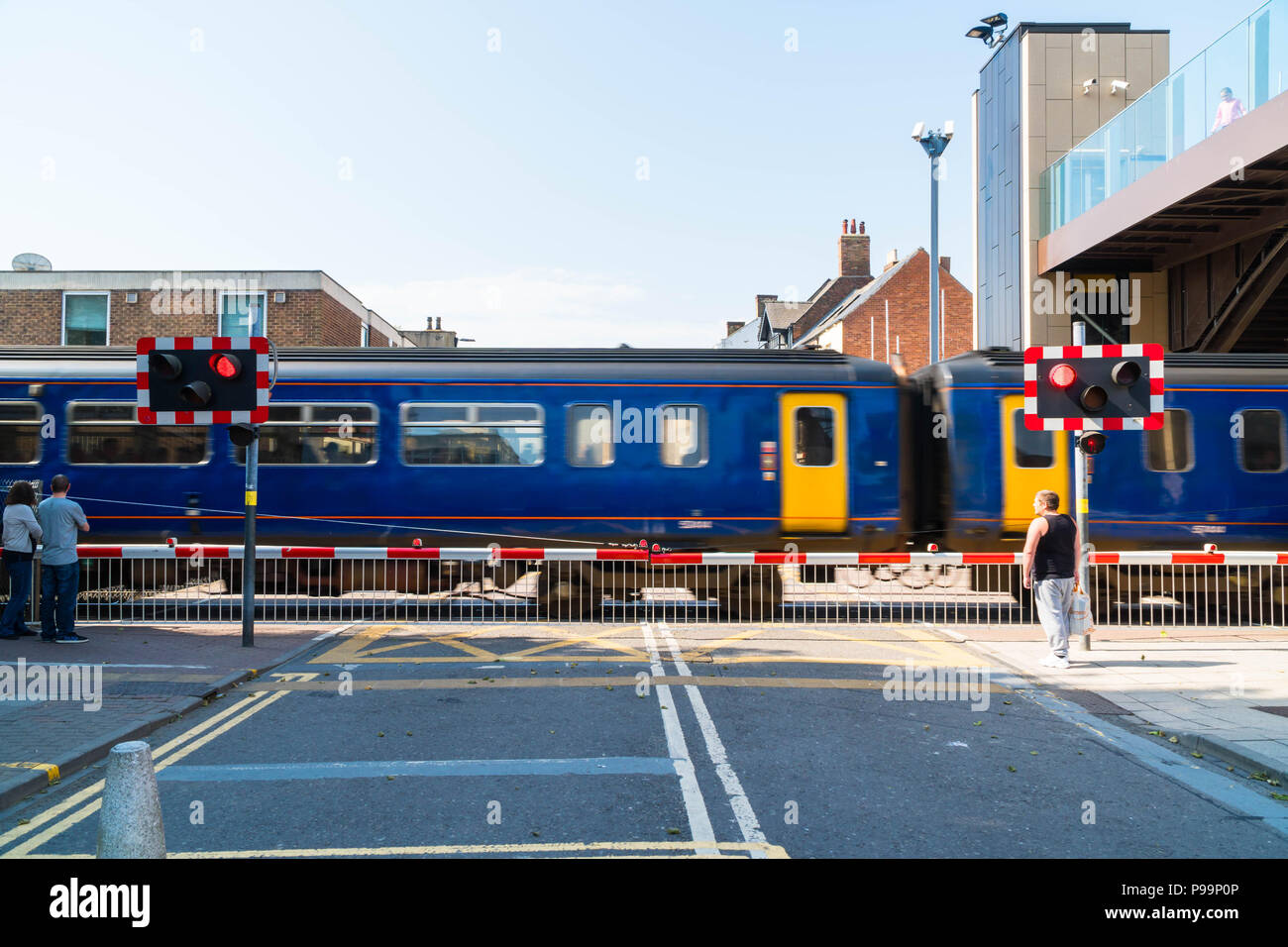 Fußgänger bei hohen Straße bahnübergang als East Midlands Zug fährt durch Lincoln Großbritannien Mai 2018 warten Stockfoto