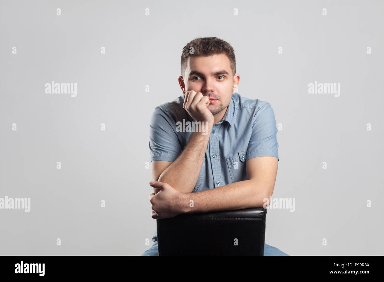 Schöner Mann sitzen und denken. Schauspieler portfolio Bild, Emotionen und Gefühle. Studio shot, auf grauem Hintergrund Stockfoto