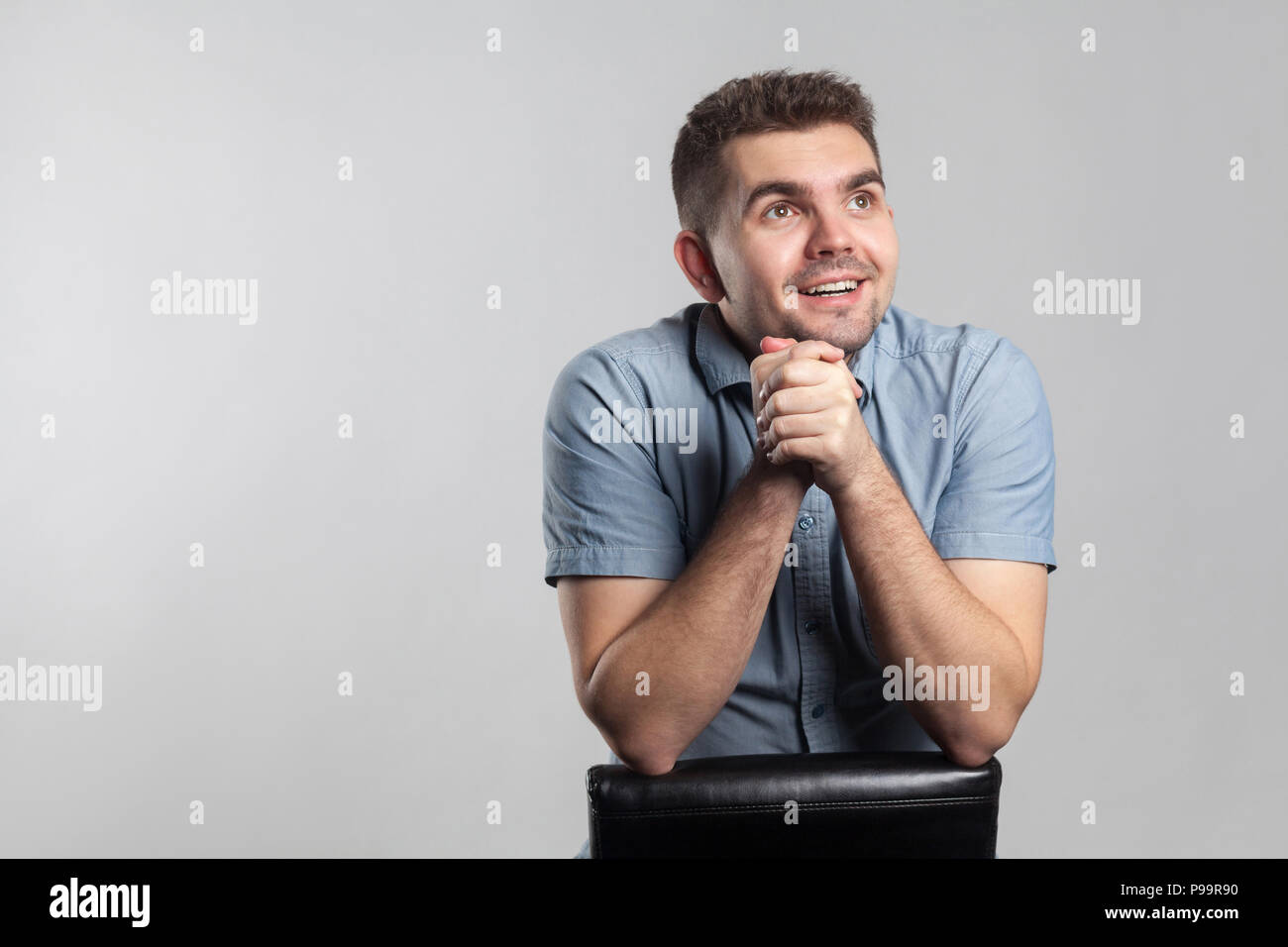 Junge erwachsene Mann wünsche und bete. Schauspieler portfolio Bild, Emotionen und Gefühle. Studio shot, auf grauem Hintergrund Stockfoto