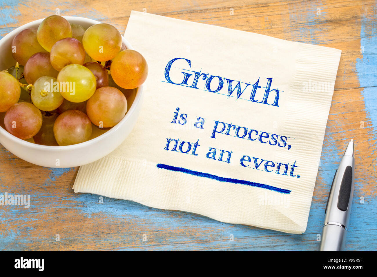 Wachstum ist ein Prozeß, kein Ereignis - Handschrift auf eine Serviette mit frischen Weintrauben Stockfoto