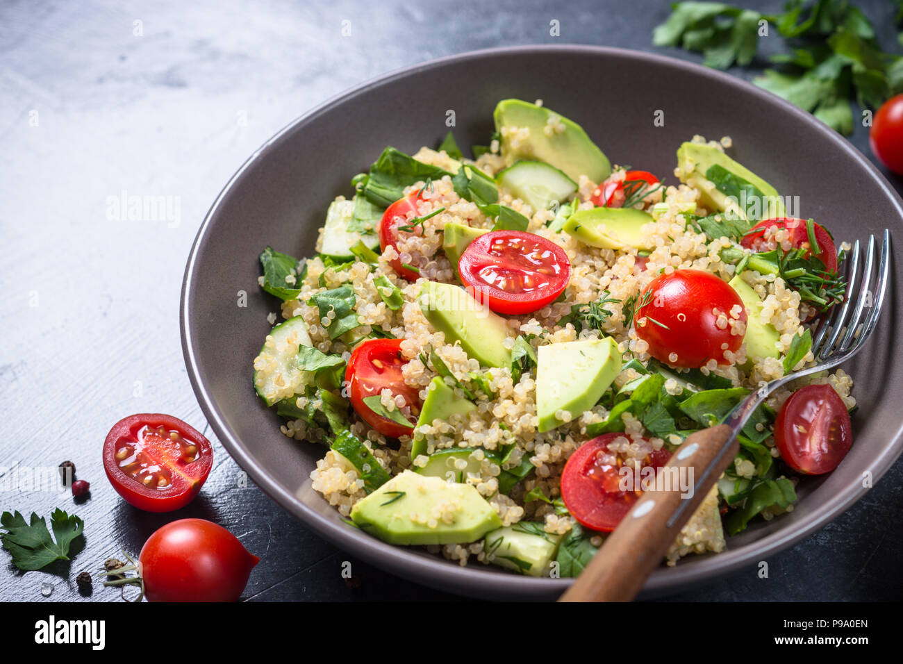 Veganes essen. Quinoa Salat mit Spinat, Avocado und Tomaten auf dunklen Tisch aus Stein. Close Up. Stockfoto