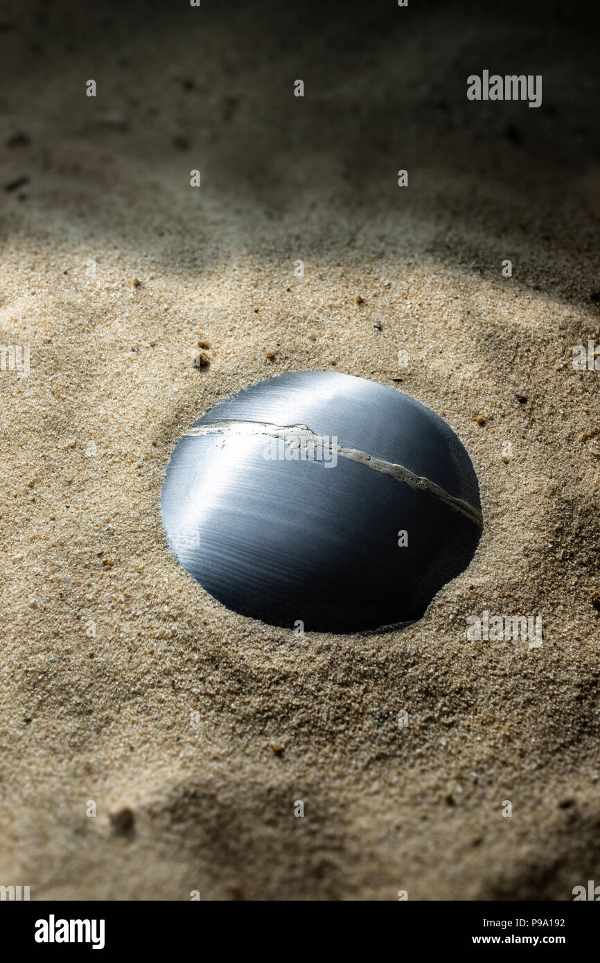 Metal orb halb im Sand begraben. Stockfoto