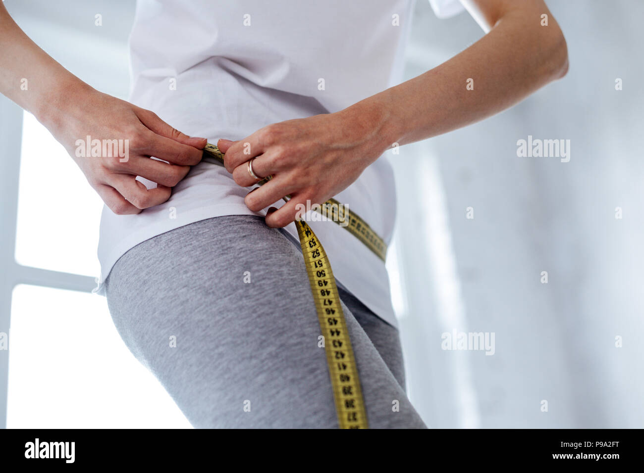 Schlanke Frau, die ihre Taille messen Stockfoto