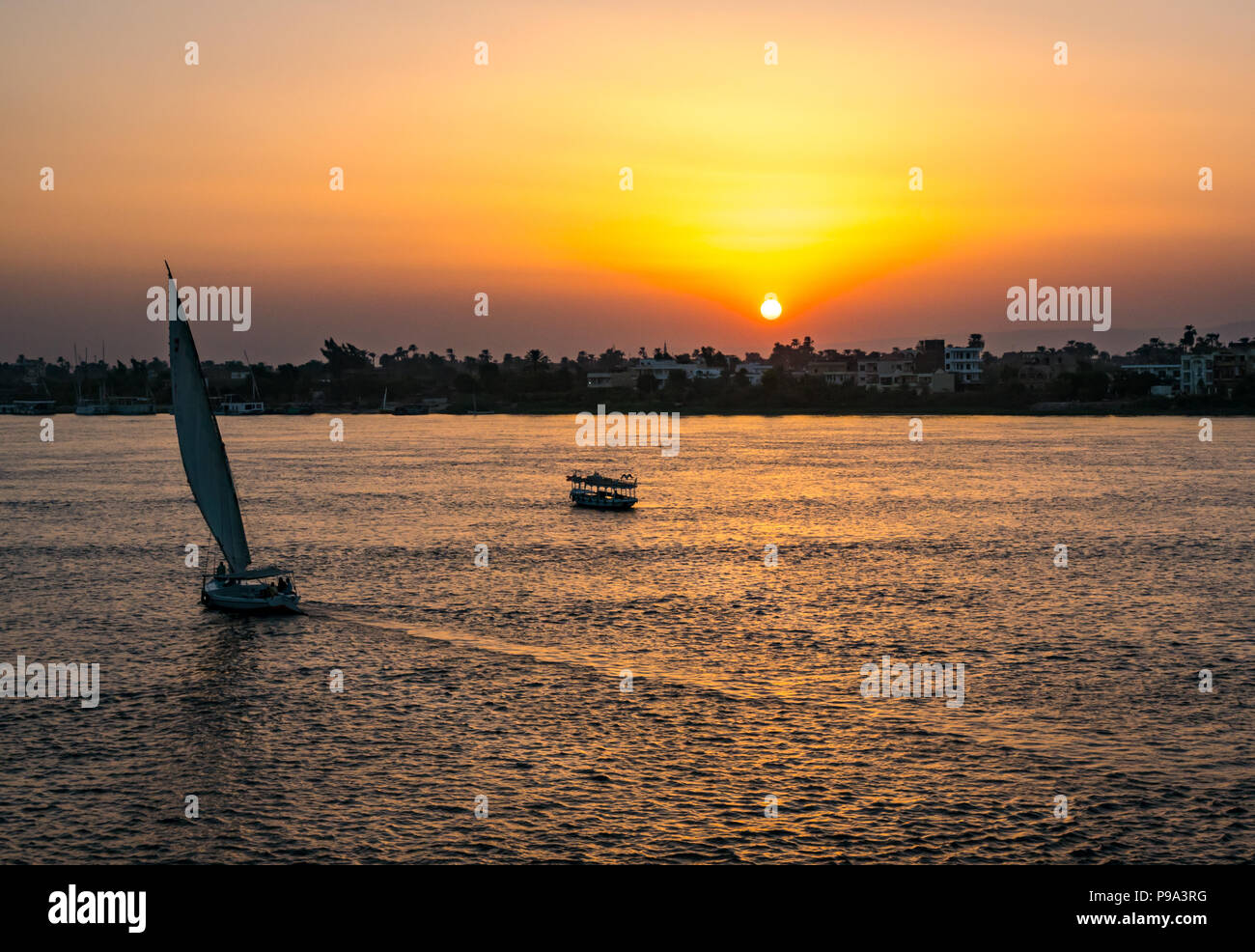 Sonnenuntergang über den Nil mit Schattenrissen von River Boat und traditionellen Feluke Segelboot, Luxor, Ägypten, Afrika Stockfoto