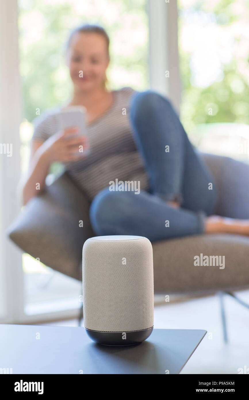 Frau streamt Musik vom Handy, kabellose Lautsprecher Stockfoto