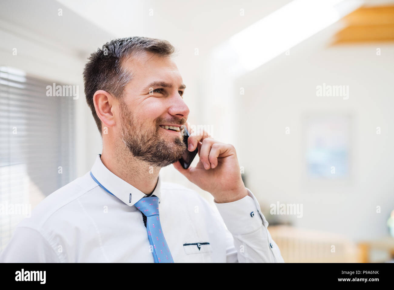 Ein junger Mann im weißen Hemd und Krawatte mit einem Smartphone. Stockfoto