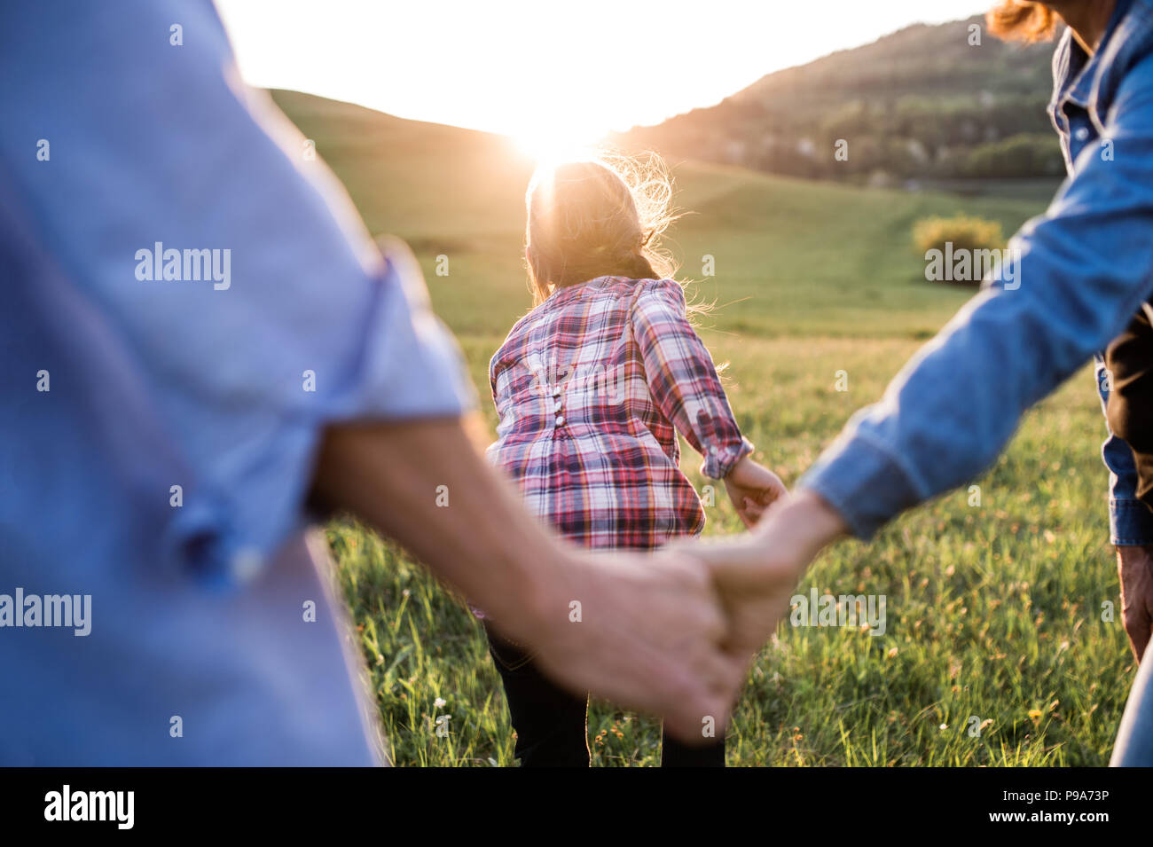 Ein kleines Mädchen mit ihrem älteren Großeltern Spaß in der freien Natur bei Sonnenuntergang. Stockfoto