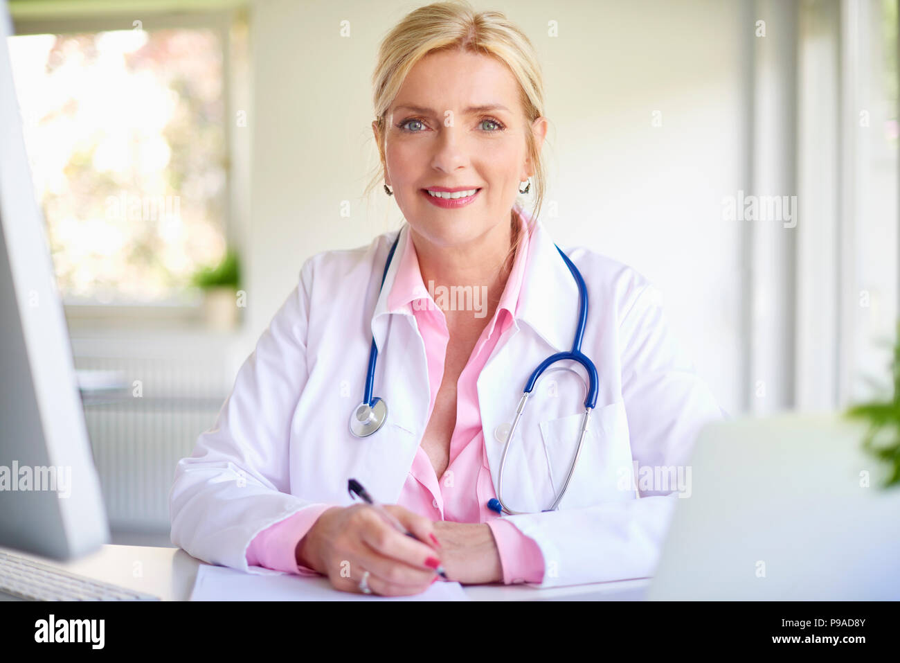 Nahaufnahme Porträt der leitenden Ärztin im Arzt Büro am Schreibtisch vor Laptop und dabei einige Schreibarbeit. Stockfoto