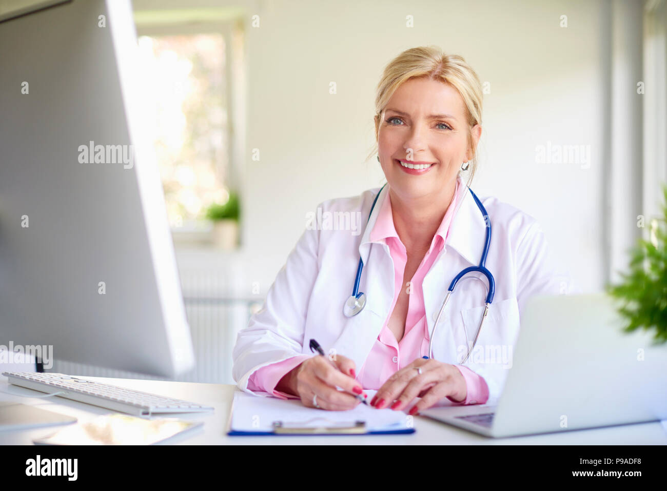 Nahaufnahme Porträt der leitenden Ärztin im Arzt Büro am Schreibtisch vor Laptop und dabei einige Schreibarbeit. Stockfoto