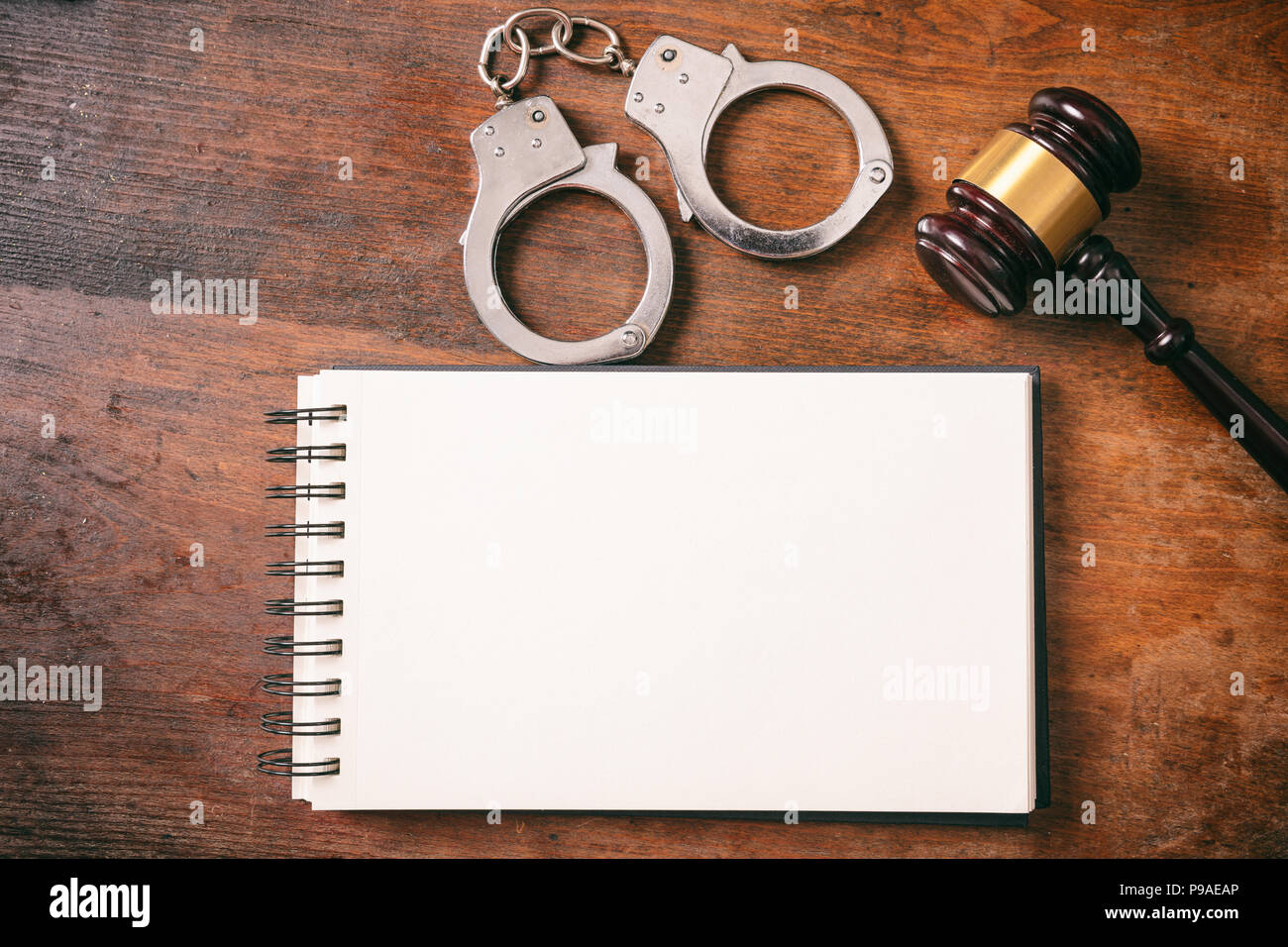 Recht und Ordnung Konzept. Handschellen, Hammer und ein Notebook auf einem hölzernen Hintergrund mit kopieren. Stockfoto