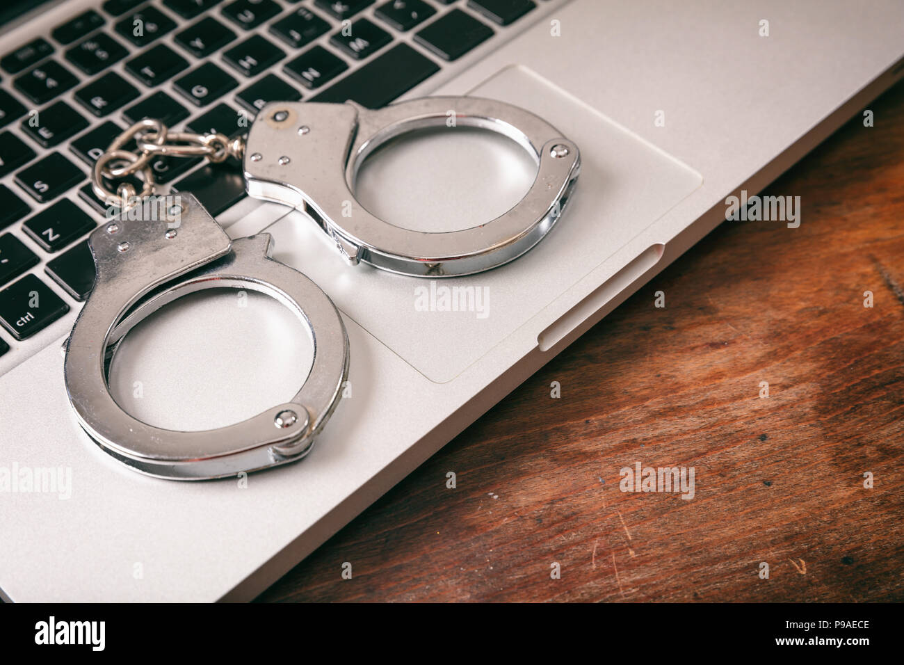 Cyberkriminalität Konzept. Handschellen auf einem Computer auf einer hölzernen Hintergrund, kopieren. Stockfoto