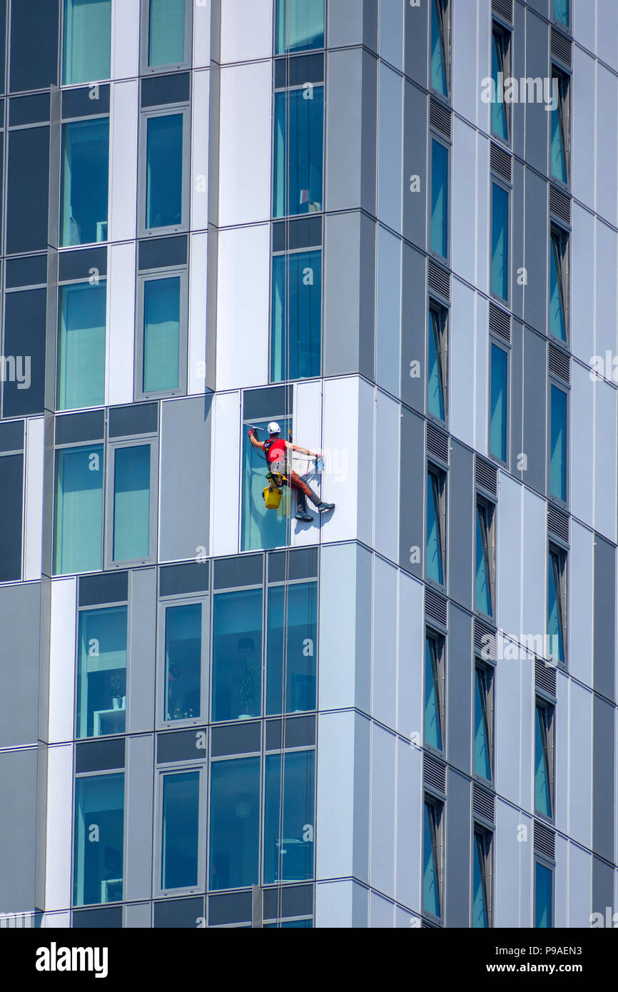 Glasreiniger auf einer der X1 MediaCity apartments Bausteine. Salford Quays, Manchester, UK. Stockfoto