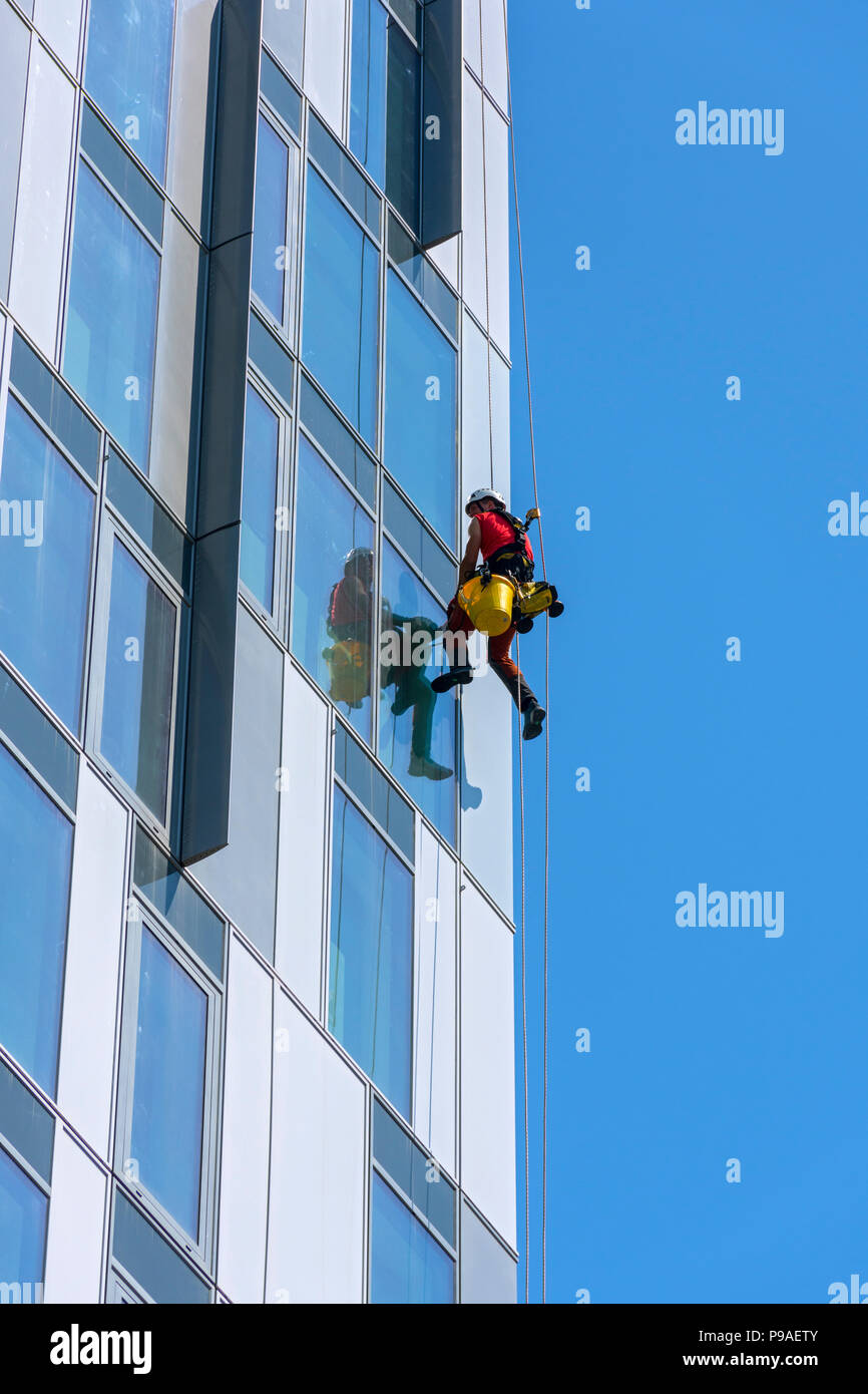 Glasreiniger auf einer der X1 MediaCity apartments Bausteine. Salford Quays, Manchester, UK. Stockfoto