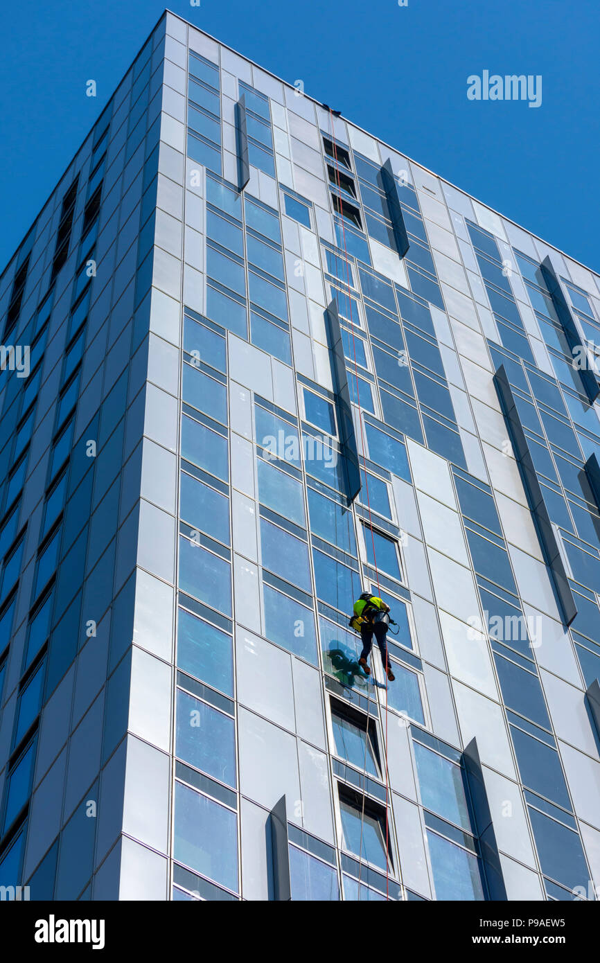 Glasreiniger auf einer der X1 MediaCity apartments Bausteine. Salford Quays, Manchester, UK. Stockfoto