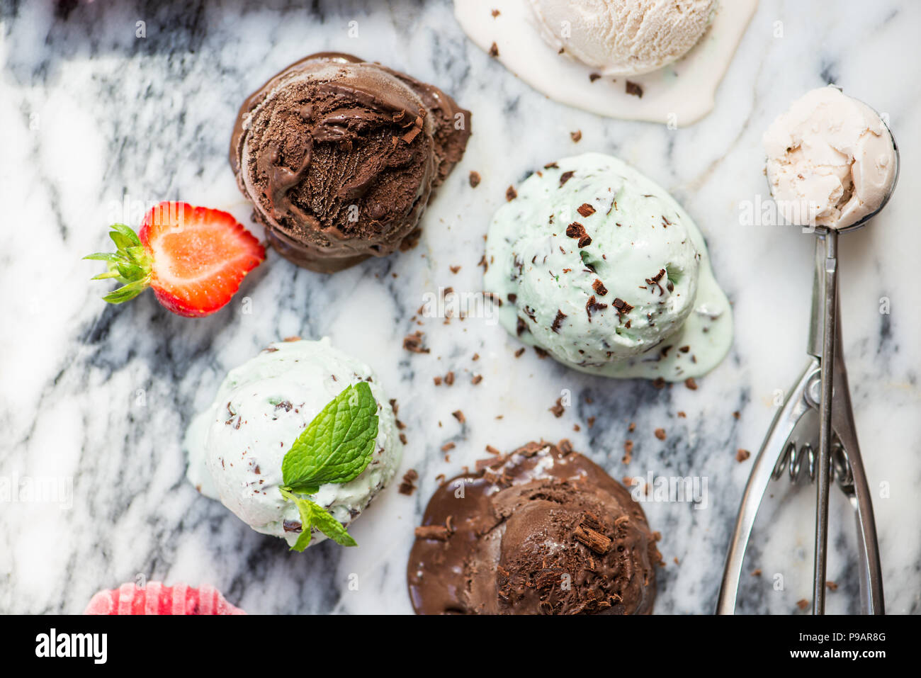 Auswahl an verschiedenen Eis Schaufeln wie Minze, Schokolade und Erdbeere auf Marmor Hintergrund, Ansicht von oben Stockfoto