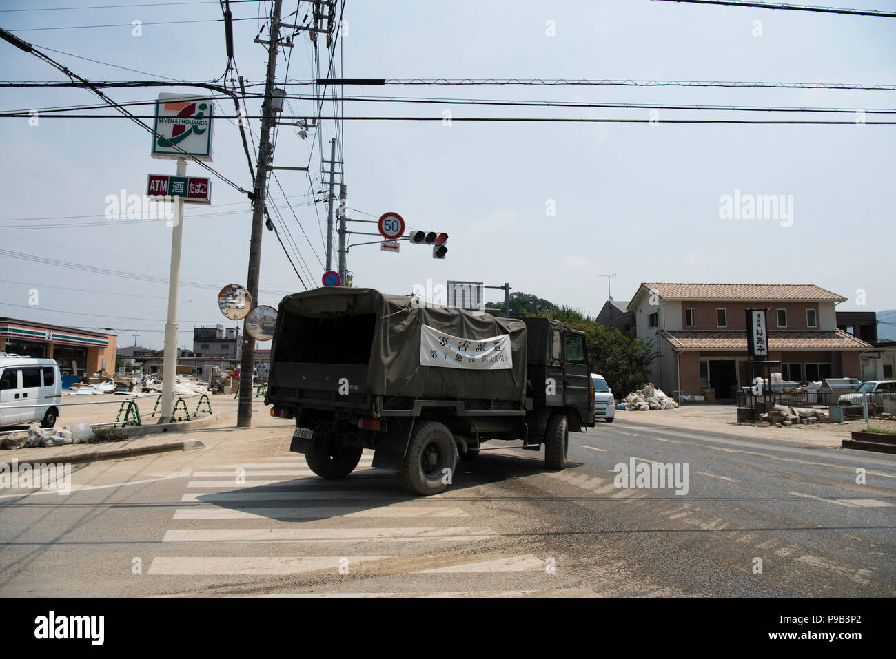 Okayama, Japan. 17. Juli 2018. Eine militärische Transport-LKW in der Flut der Bereinigung beim Mabicho, Kurashiki, Okayama Präfektur, Japan beteiligt. Mehr als 200 Tote bei Überschwemmungen und Erdrutschen durch sintflutartige Regenfälle vor mehr als einer Woche verursacht. Am Sonntag kündigte die Regierung das Wetter bei einem extrem schweren Katastrophe bezeichnet werden würde, wodurch Mittel für die Wiederherstellung der betroffenen Gebiete. Aufräumarbeiten und Wiederaufnahme Bemühungen wurden durch extreme Hitze behindert wurde. Quelle: Lba Co.Ltd./Alamy leben Nachrichten Stockfoto