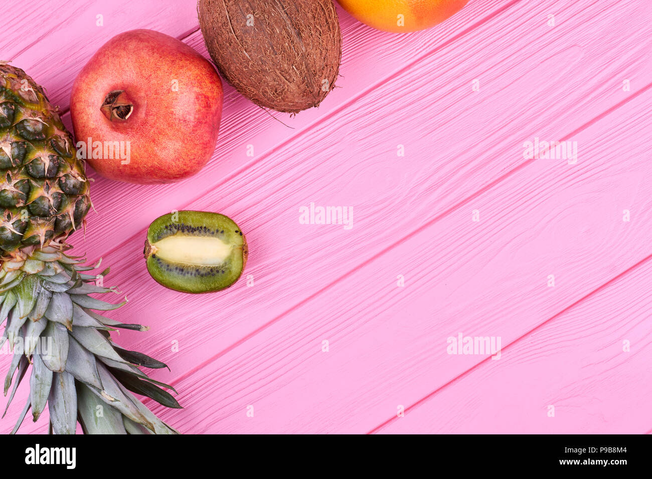 Bunte tropische Früchte und Kopieren. Grenze von exotischen Früchten auf rosa Holz und Text. Vorteile von Bio-Lebensmitteln. Stockfoto
