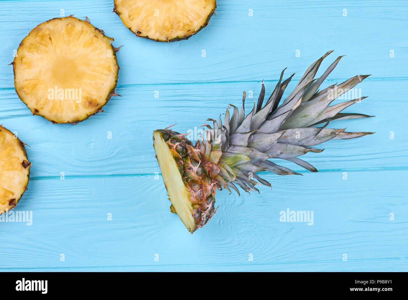 Frisch geschnittene Kreis Scheiben Ananas. Flach Ananas Krone auf Blau Holz- Oberfläche. Gesunde Essbare Pflanze. Stockfoto