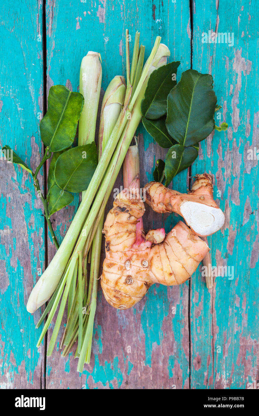 Frischer Galgant mit Zitronengras und Kaffernlimette Blätter von oben auf Holztisch. Stockfoto