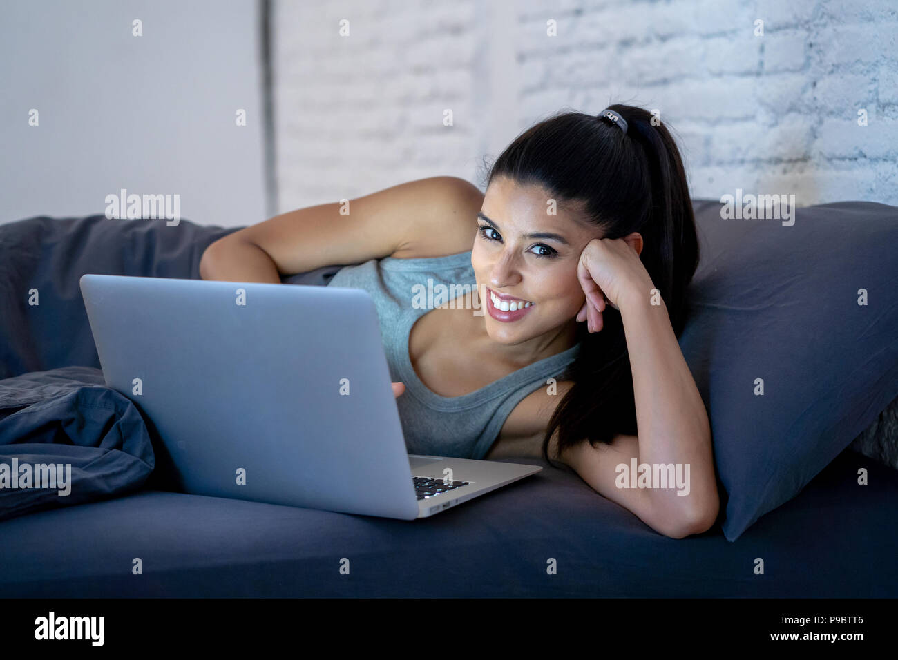 Junge attraktive und glücklichen Asiatischen Hispanic ethnisch gemischte Frau im Bett mit Laptop Computer studieren oder genießen Sie das Internet in Technologie und lifes Stockfoto