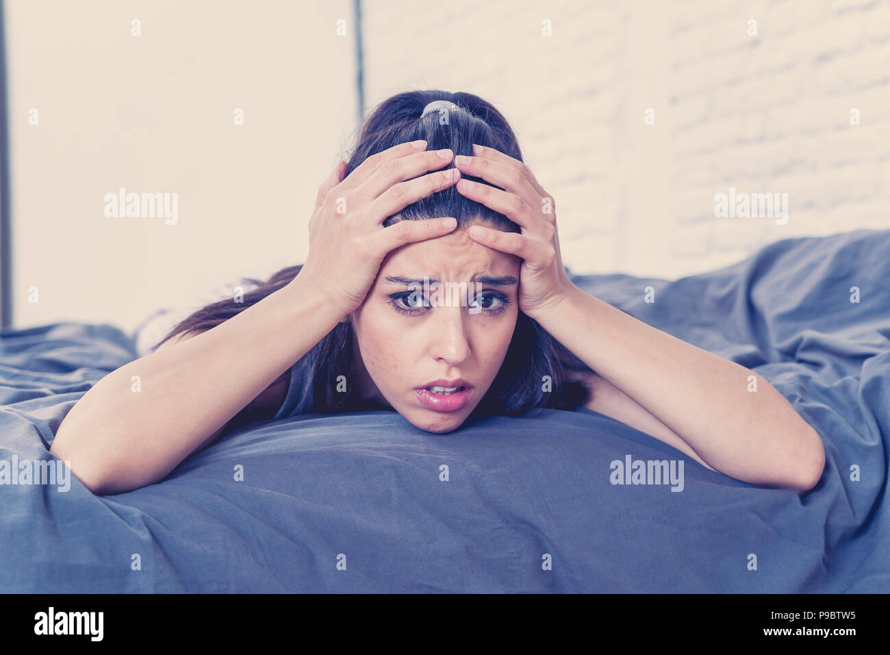 Junge schöne Hispanic traurige Frau portrait ernst und besorgt, besorgt und nachdenklichen Gesichtsausdruck Gefühl auf dem Bett gedrückt mit Weiß Stockfoto