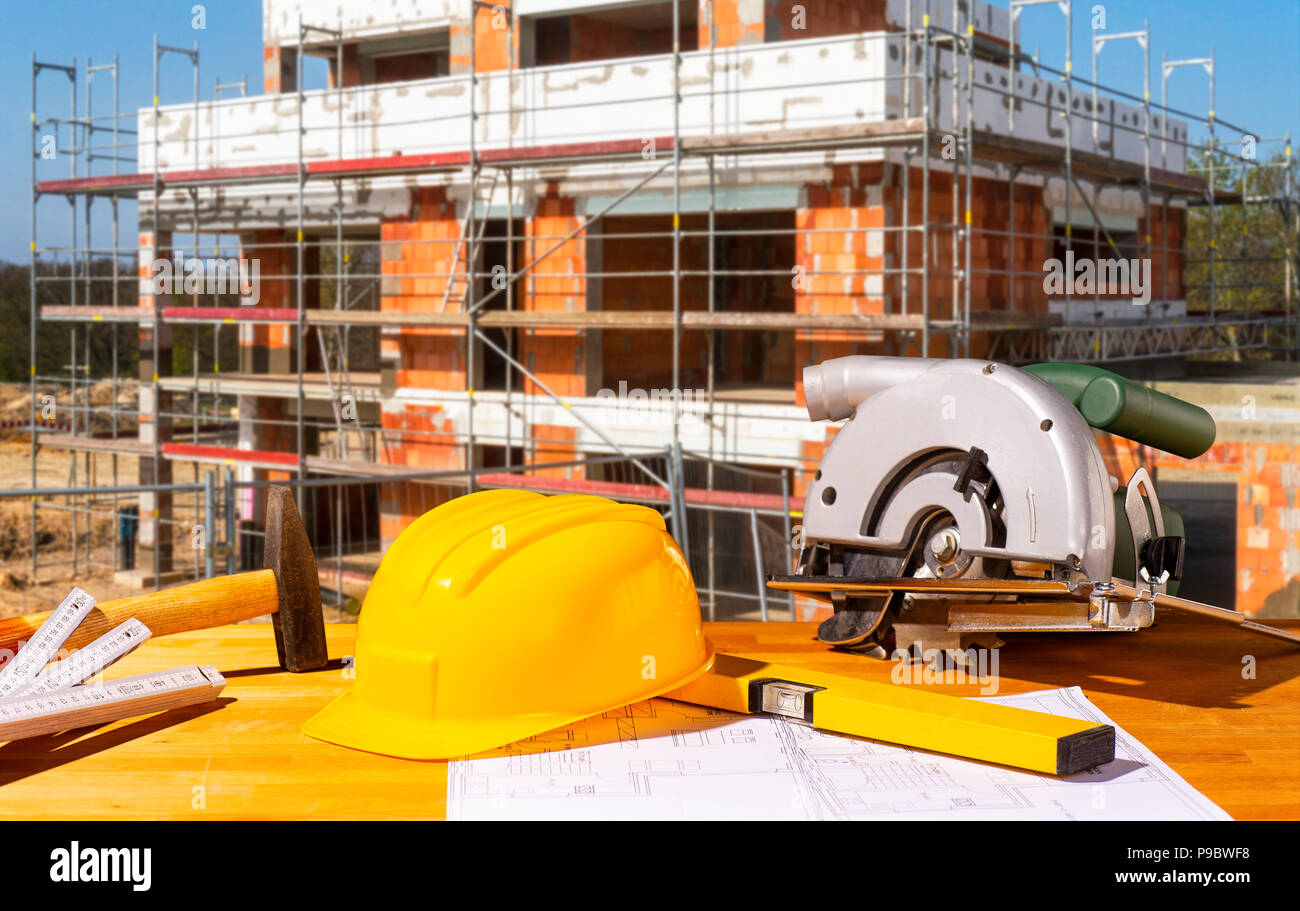 Helm, Werkzeuge und Kreissäge mit einer Shell im Hintergrund Stockfoto