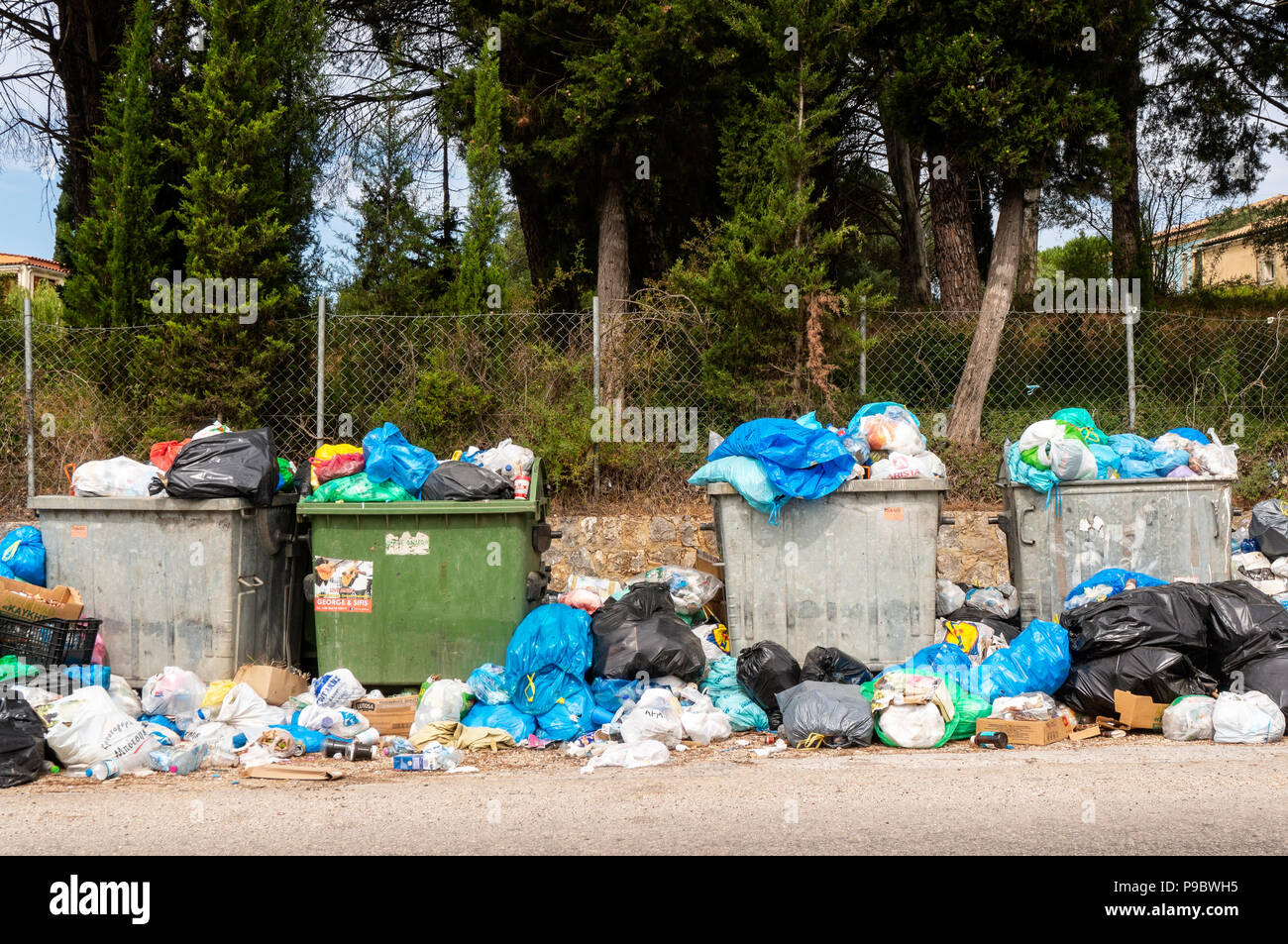 Müllcontainer und Müllsäcke sind auf der griechischen Insel Korfu am Straßenrand Stockfoto