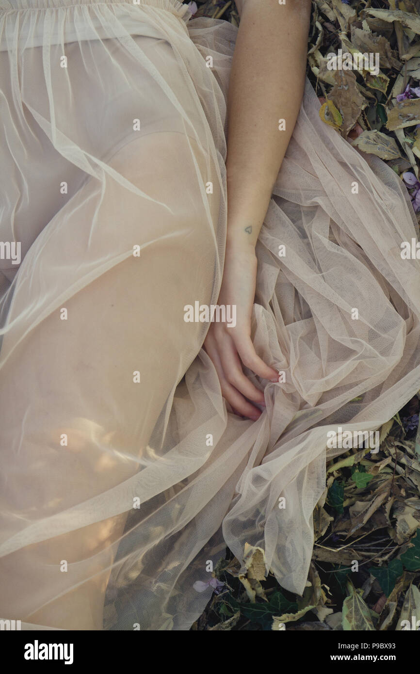 Ein Mädchen in einem transparenten Kleid im Wald liegen Stockfoto