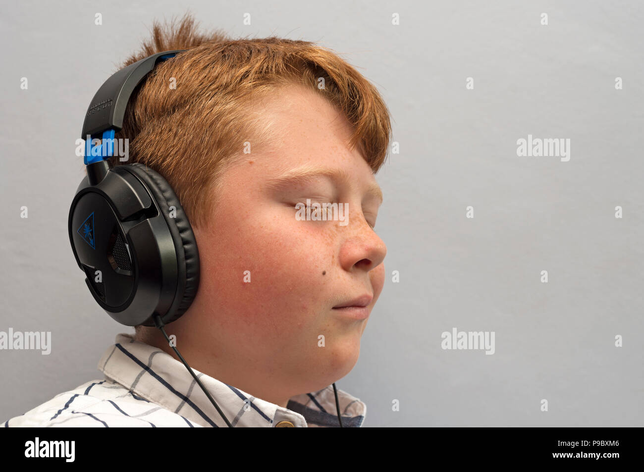 12-jähriger Junge das Hören von Musik über Kopfhörer Stockfoto