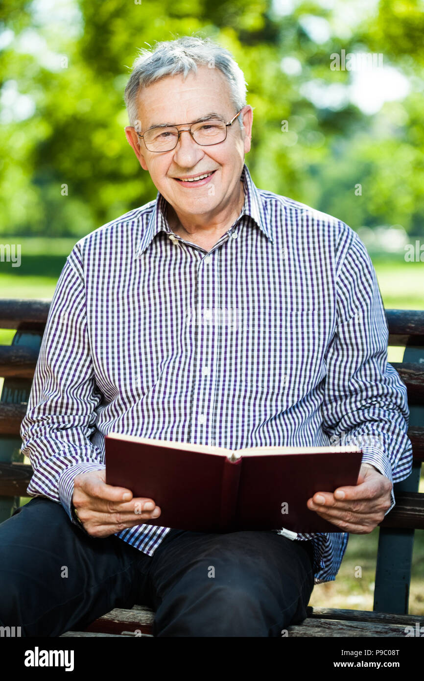 Älterer Mann ein Buch lesen im Park Stockfoto