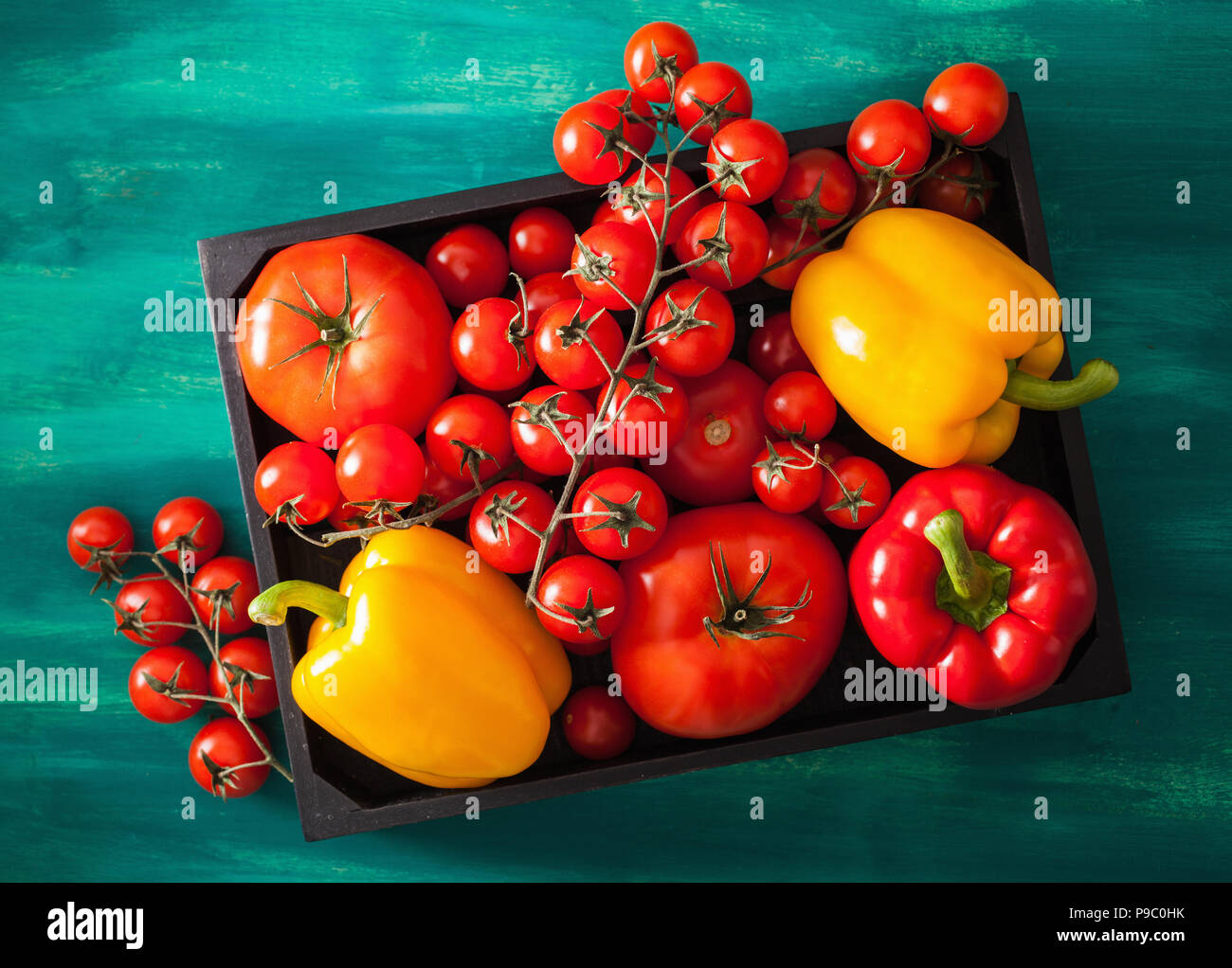 Sortierte Tomaten und Paprika in Holzkiste Stockfoto