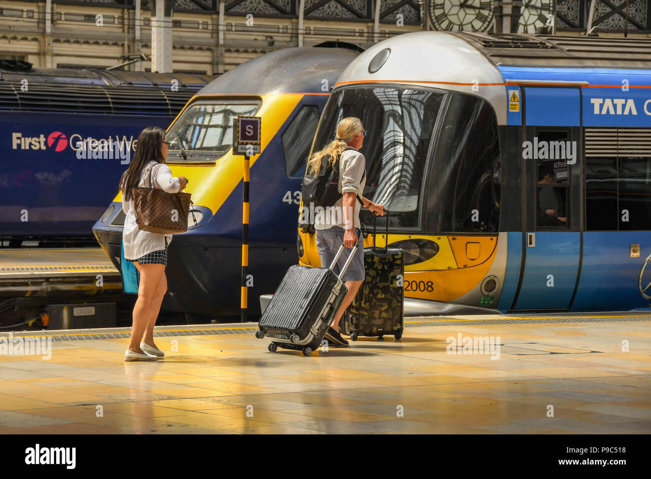 Mann und Frau entlang eine Plattform am Londoner Bahnhof Paddington und dem Heathrow Express an Bord Stockfoto